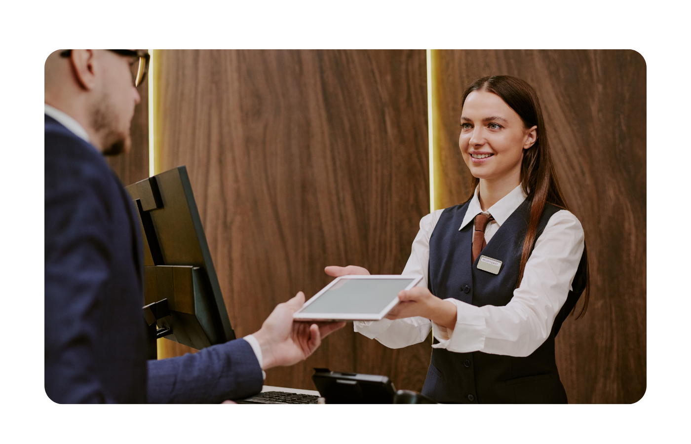 Recepcionista de hotel gestionando la atención al cliente junto a agente de voz con inteligencia artificial